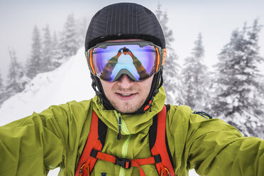 Close up of male skier wearing ski goggles taking selfie on mountain at Kranzegg, Bavaria, Germany - CUF22846