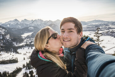 Hiking couple taking selfie overlooking snow covered Allgau Alps, Bavaria, Germany - CUF22848