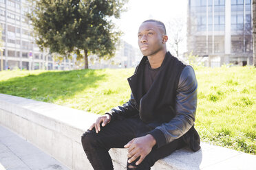 Young man sitting on wall, outdoors, pensive expression - CUF22927