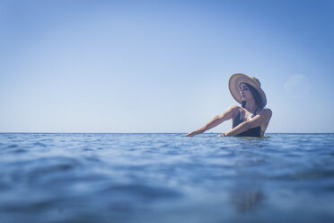Junge Frau mit Sonnenhut watet im tiefblauen Meer, Villasimius, Sardinien, Italien - CUF22959