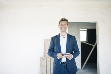 Portrait of smiling man in suit in building under construction - MOEF01231