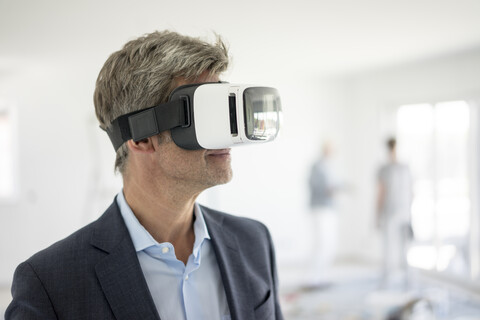 Mann im Anzug mit VR-Brille in einem im Bau befindlichen Gebäude, lizenzfreies Stockfoto