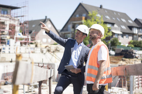 Man in suit talking to construction worker on construction site - MOEF01252