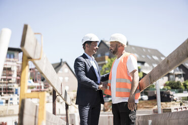 Man in suit shaking hands with construction worker on construction site - MOEF01255