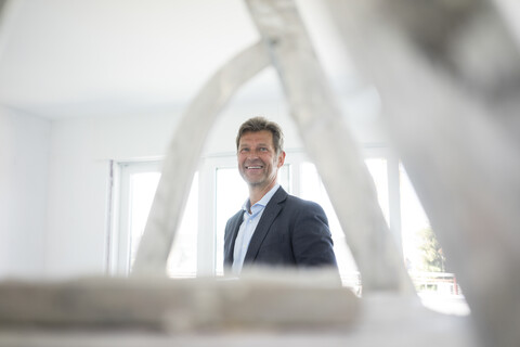 Porträt eines lächelnden Mannes im Anzug in einem im Bau befindlichen Gebäude, lizenzfreies Stockfoto