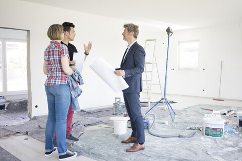 Man in suit talking to couple in unfinished building stock photo