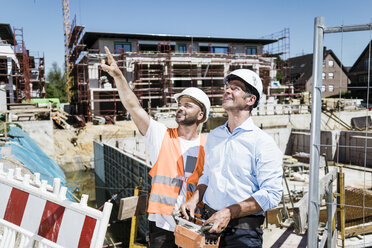 Lächelnder Bauarbeiter im Gespräch mit einem Mann auf der Baustelle - MOEF01272