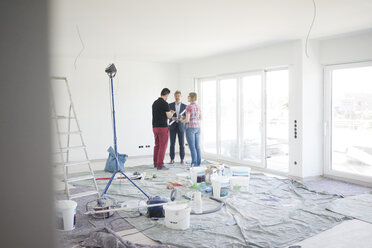 Man in suit talking to couple in unfinished building - MOEF01274