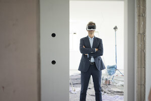 Mann im Anzug mit VR-Brille in einem im Bau befindlichen Gebäude - MOEF01278