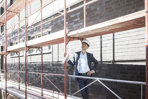 Architekt mit Schutzhelm auf einem Baugerüst auf einer Baustelle - MOEF01292