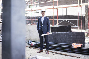 Confident architect wearing hard hat standing on construction site - MOEF01296