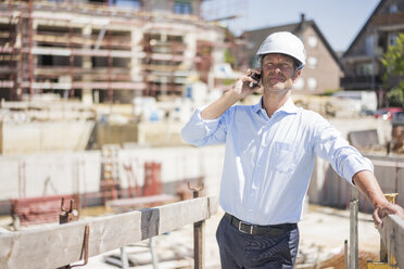 Man wearing hard hat on cell phone on construction site - MOEF01306