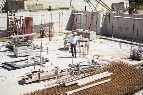 Mann mit Schutzhelm auf einer Baustelle schaut sich um, lizenzfreies Stockfoto