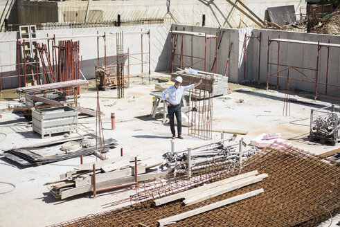 Mann mit Schutzhelm auf einer Baustelle schaut sich um - MOEF01308