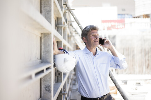 Mann mit Mobiltelefon auf einer Baustelle, lizenzfreies Stockfoto