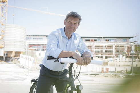 Portrait of man with e-bike on construction site - MOEF01321