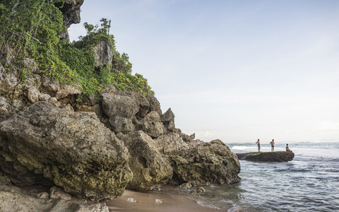 Drei Männer auf einem Küstenfelsen am Panawa Beach, Bali, Indonesien, lizenzfreies Stockfoto