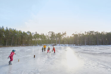 Älteres Ehepaar und Enkelkinder üben Eislaufslalom auf einem zugefrorenen See, Gavle, Schweden - CUF23019