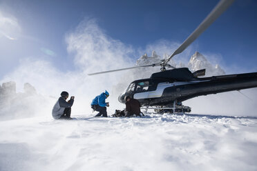 Drei männliche Snowboarder beim Verlassen eines Hubschraubers, Trient, Schweizer Alpen, Schweiz - CUF23027