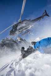 Hubschrauber verlässt männliche Snowboarder auf dem Berg, Trient, Schweizer Alpen, Schweiz - CUF23028