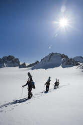 Vier männliche Snowboarder wandern durch eine verschneite Landschaft, Trient, Schweizer Alpen, Schweiz - CUF23031