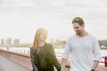 Romantic couple strolling on waterfront at sunset, Battersea Park, London, UK - CUF23083