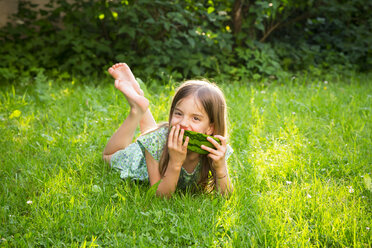 Porträt eines kleinen Mädchens, das auf einer Wiese liegt und Wassermelone isst - LVF07035