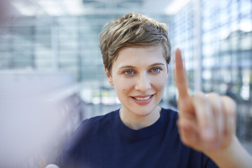 Portrait of blond businesswoman touching at glass pane - PNEF00702