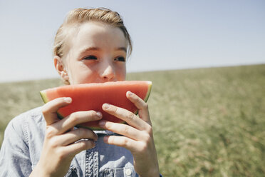 Junge auf einem Feld, der eine Wassermelone isst - KMKF00290