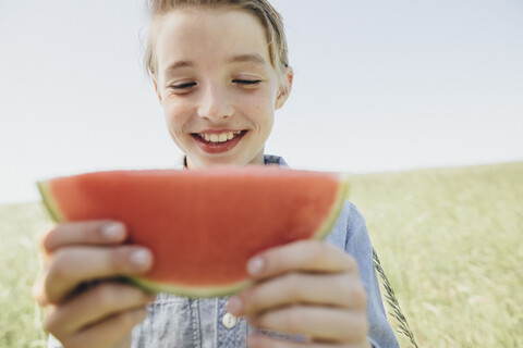 Happy boy on a field eating a watermelon stock photo