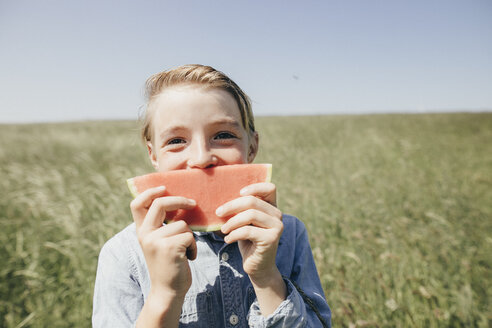 Glücklicher Junge auf einem Feld mit einer Wassermelone in der Hand - KMKF00292