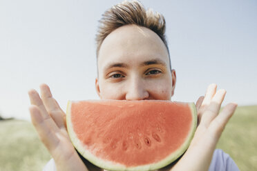 Porträt eines jungen Mannes, der eine Wassermelone im Freien hält - KMKF00294