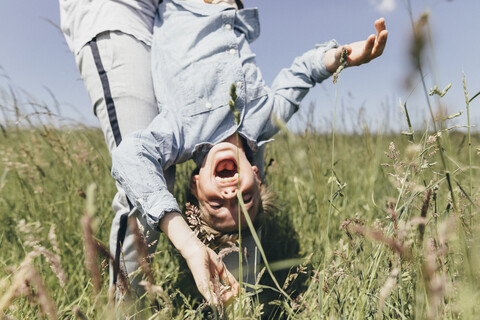 Mann trägt glücklichen Jungen auf einem Feld, lizenzfreies Stockfoto