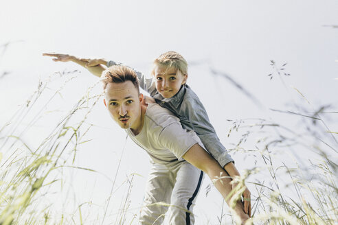 Junger Mann und Junge auf einem Feld, die so tun, als würden sie fliegen - KMKF00308