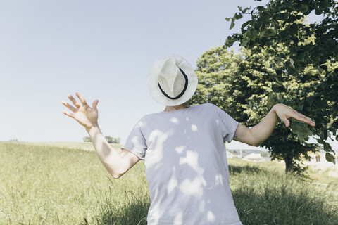 Man covering his face with a hat in field stock photo