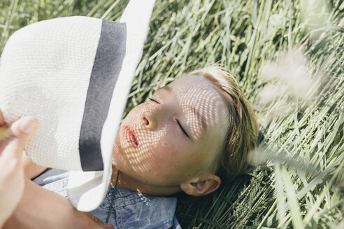 Boy with a hat lying in field - KMKF00312