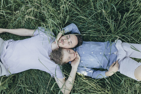 Young man and boy lying in field stock photo