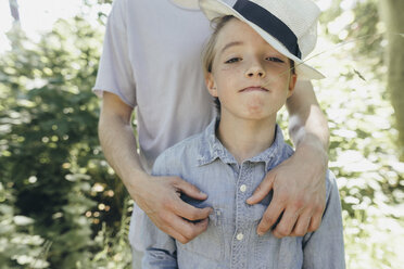 Portrait of boy wearing hat being embraced by a man - KMKF00322