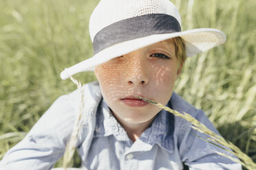 Portrait of boy wearing a hat sitting in field - KMKF00340