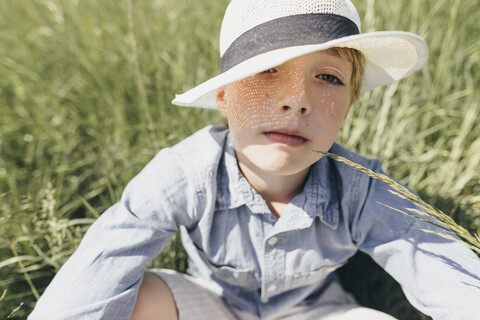 Portrait of boy wearing a hat sitting in field stock photo