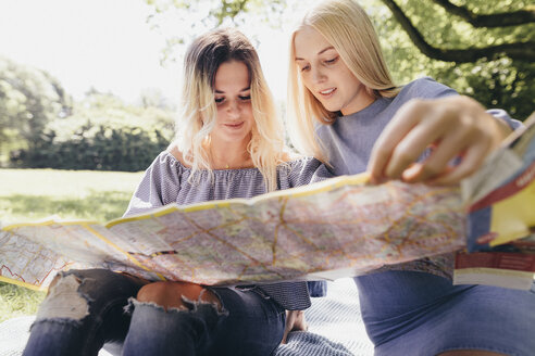 Zwei junge Frauen betrachten eine Karte in einem Park - KMKF00347