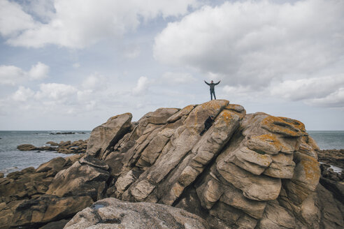 Frankreich, Bretagne, Meneham, Mann steht auf Felsformation an der Küste - GUSF00963