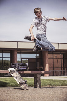 Männlicher Highschool-Schüler macht Mid-Air-Skateboard-Trick außerhalb der Highschool - ISF08856
