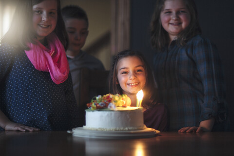 Girl with birthday cake surrounded by friends stock photo