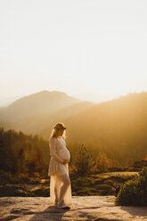 Schwangere Frau in den Bergen, die ihren Bauch berührt, Sequoia-Nationalpark, Kalifornien, USA - ISF08883