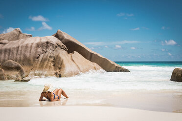 Rückansicht einer mittleren erwachsenen Frau im Bikini, die sich am Strand vor blauem Himmel entspannt, Seychellen - FSIF03020