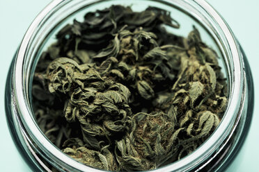 High angle view of marijuana leaves in glass jar on table against black background - FSIF03026