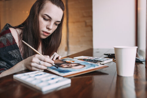 Schöne junge Frau malt im Café - FSIF03050