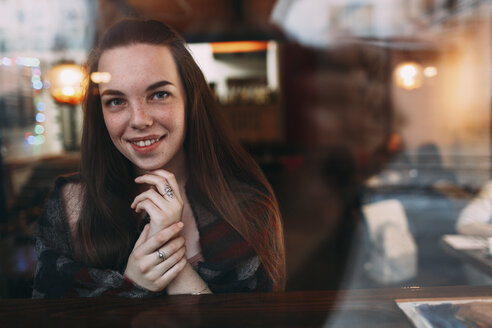 Lächelnde schöne junge Frau durch das Fenster eines Cafés gesehen - FSIF03051