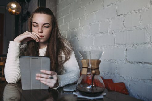 Junge Frau benutzt digitales Tablet in einem Café - FSIF03052